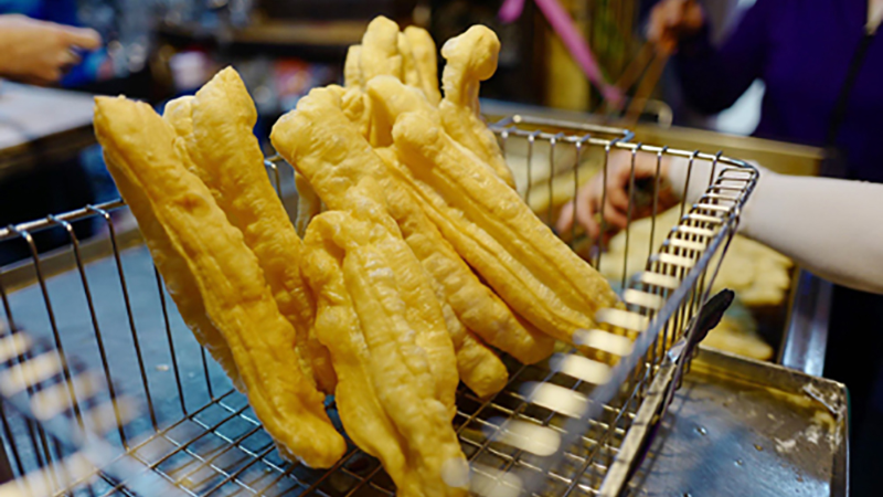 Vendor frying Hanoi bagel twists at a street stall